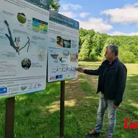 le maire du rouget devant des panneaux informatifs et un lac vide