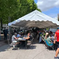 des personnes dégustent un barbecue sous un chapiteau
