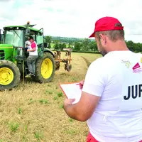 Un monsieur juge un tracteur en train de labourer