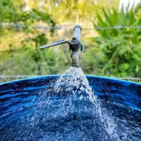 robinet d'eau ouvert au dessus d'un baquet