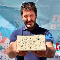 Nicolas Cussac tient dans ses mains une demi fourme de bleu d'Auvergne
