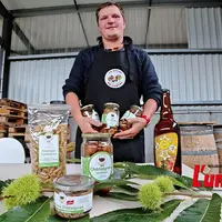 Un homme en tablier noir présente une gamme de produits transformés à base de châtaignes.
