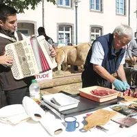 Un joueur d'accordéon et un cuisinier qui prépare de la viande aubrac