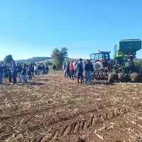 Elèves et adhérents de Cuma devant un tracteur et semoir semis-direct 6 m équipés des systèmes GPS, autoguidage, Isobus.
