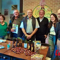 Un groupe de personnes débout, devant une table remplie de produits à la châtaigne.