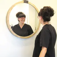 Une dame souriante face à un miroir.
