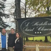 Deux hommes et une femme devant le panneau de l'hostellerie
