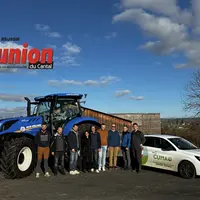 Un groupe de personnes devant un tracteur bleu.