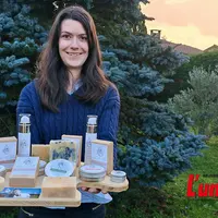 une jeune femme présente sur un plateau de bois des cosmétiques et savons au lait de jument
