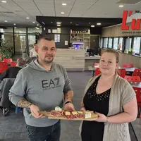 Deux personnes portent un plat de charcuterie.