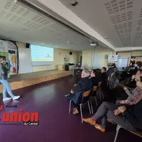 une sale avec une personne debout à gauche s'adressant à un groupe de personnes à droite de la photo
