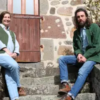 Une jeune femme et un jeune homme posant, assis sur les escaliers d'une vieille maison en pierre