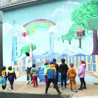 Des enfants regardent une fresque sur un mur.