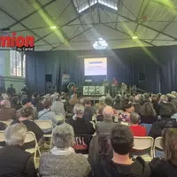 des gens de dos dans une salle avec au fond un écran lumineux