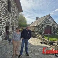 Une femme et un homme devant une maison en pierre
