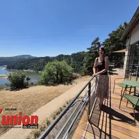 Une femme debout avec à sa droite le lac de Garabit.