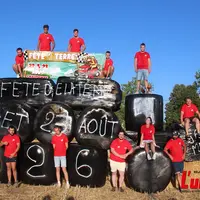 groupe de jeunes agriculteurs en maillot rouge sur un tracteur fait de ballots de foin