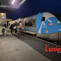 à gauche de la photo des gens montent dans un train bleu.
