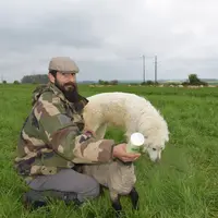 <p>Avec son chien patou Timber, Bastien Devriendt biberonne la seule agnelle qui n’a pas été adoptée par sa mère.</p>