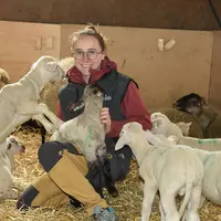 Pauline Jouve avec un agneau dans sa bergerie