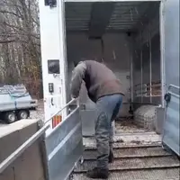 Une personne installe des claies coulissantes sur un quai de chargement.