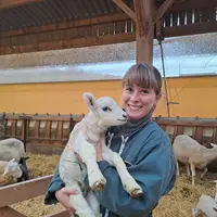 Une éleveuse tient dans ses bras un agneau.
