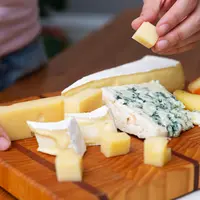 Une femme prend un bout de fromage d'un plateau.