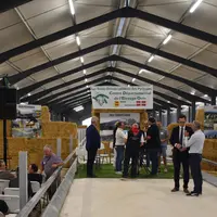Intérieur d'une bergerie aménagée pour l'inauguration, avec personnalités importantes.