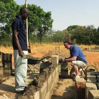 Les murs de la porcherie sont montés par les bénévoles avec les maçons locaux, en utilisant des parpaings fabriqués sur place.