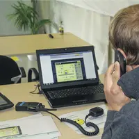 Un homme au téléphone deavnt un écran d'ordinateur pour asssister un chauffeur.