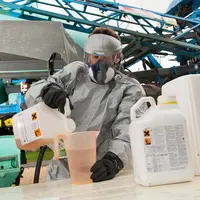 Professionnel manipulant des pesticides devant un pulvérisateur