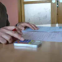 Personne devant une déclaration fiscale avec une calculatrice.