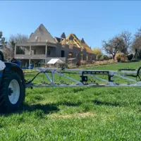 Pulvérisateur dans un champ avec maison en construction à l'arrière