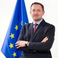 Christophe Hansen, Commissaire européen désigné pour l'Agriculture, devant un drapeau européen