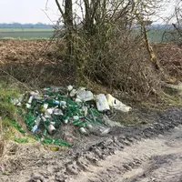 Déchets près d'un terrain agricole. On voit des bouteille en verre.