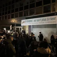 Des agriculteurs au petit matin devant l'Inrae sous une banderole avec l'inscription "à vendre, ne sert plus à rien"