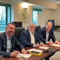 les différents partenaires assis autour d'un bureau pour signer le partenariat
