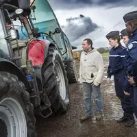 Gendarmes discutant avec un agriculteur devant un tracteur