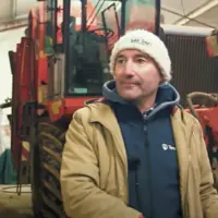 Bruno Cardot dans un hangar devant des tracteurs