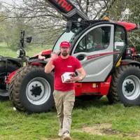 un homme posant devant une engin manitou
