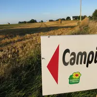 panneau avec la mention "camping" devant un champ
