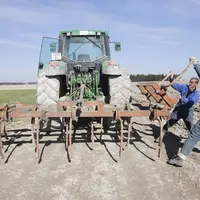 Deux agriculteurs mettant en place une herse de 4 mètres pour préparer les bords de champs