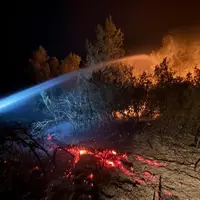 Lance à eau ciblant les flammes et les braises en soirée lors de l'incendie historique ayant touché l'Aude depuis le 5 août.