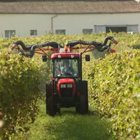 Une agricultrice dans son tracteur traite des pieds de vignes grâce à des pulvérisateurs. 
