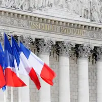 drapeaux français flottant devant la façade de l'Assemblée nationale