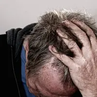 homme en détresse se tenant la tête dans les mains