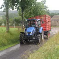 tracteur avec une remorque circulant sur un chemin de campagne