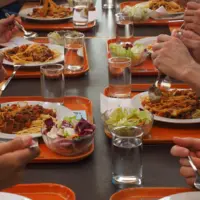 restauration collective gros plan sur une table avec des personnes en train de manger