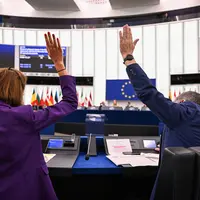 Deux députés européens levant la main pour voter au sein du Parlement européen.