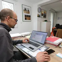 Un homme assis devant un ordinateur portable sur un bureau